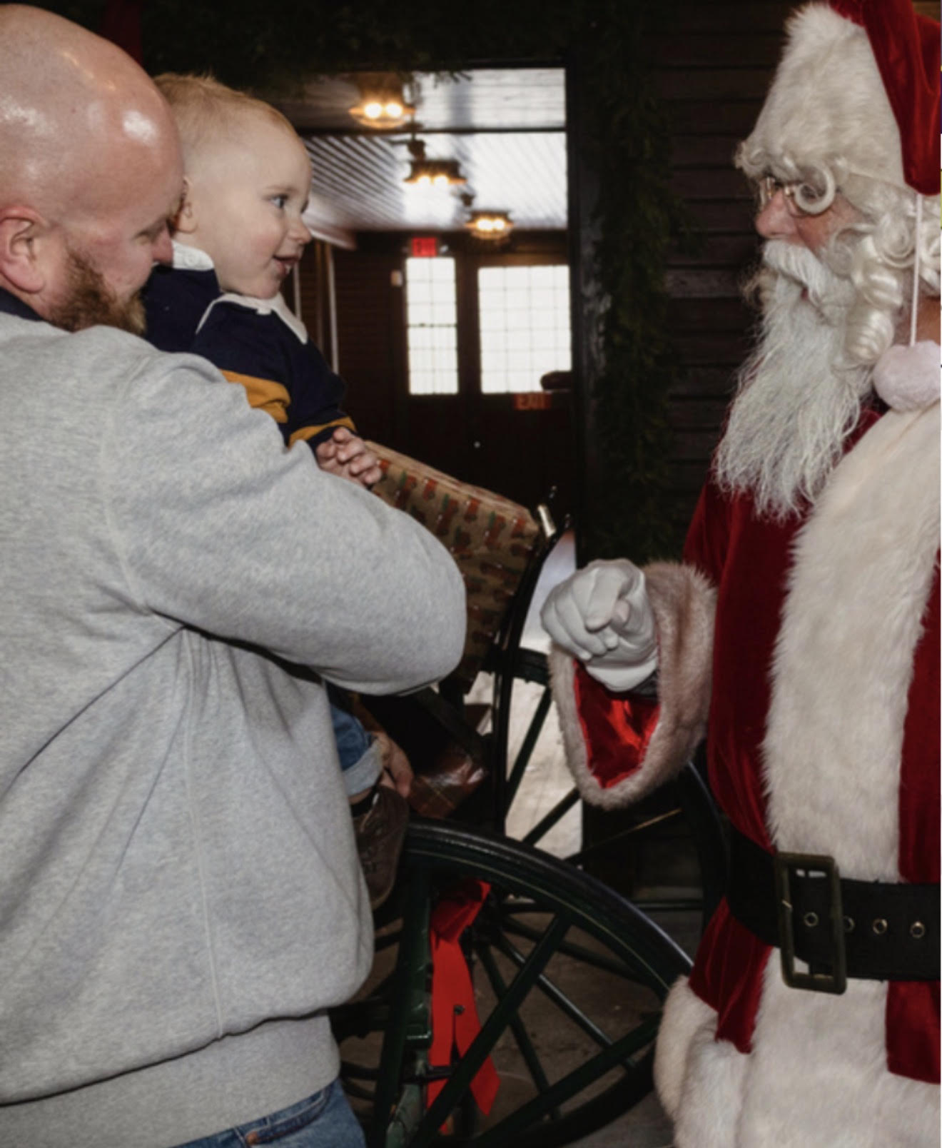 Santa holding a baby on a snowy doorstep during a home visit in Danvers, Massachusetts